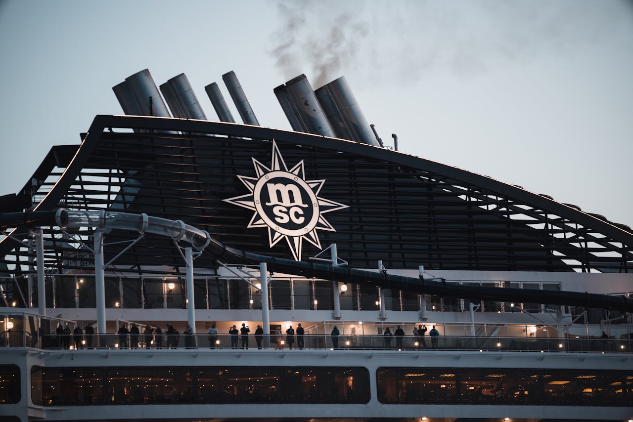 Passengers enjoy the evening view on the MSC cruise ship deck with smoke stacks.